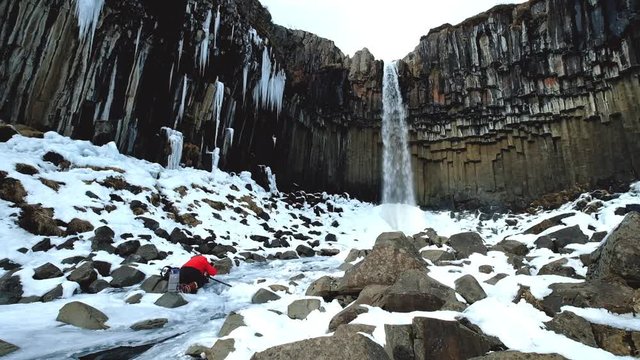Svatifoss waterfall in winter at Iceland, with one photographer traveler setting camera 