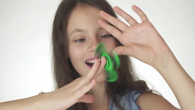 Beautiful cheerful teen girl playing with green fidget spinner on white background stock footage video