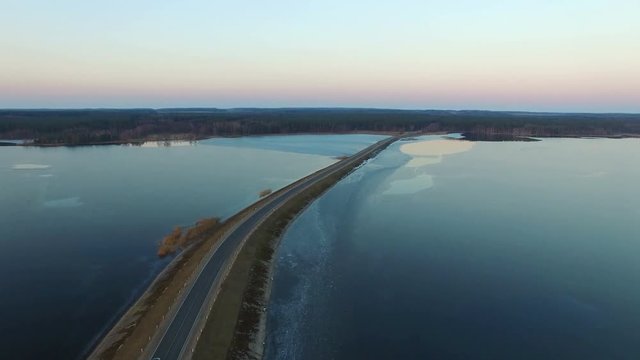 4K. Flight over road in the frozen lake in winter on sunset, aerial view.