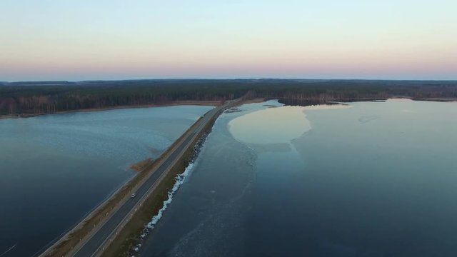 4K. Flight over road in the frozen lake in winter on sunset, aerial view.