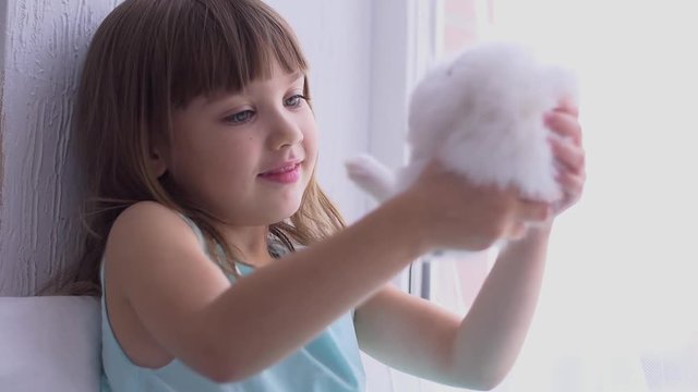 Pretty teen girl having fun, hugging and playing with decorative rabbit