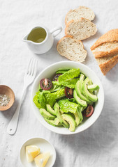 Avocado, romano, kumato tomatoes salad and whole wheat branny bread on light background, top view. Healthy diet vegetarian food concept