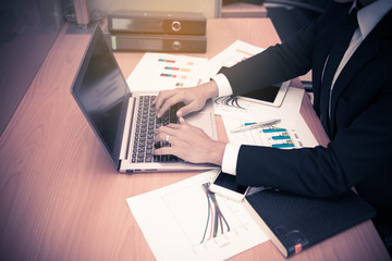 Asian businessman working on the desk with laptop,smart phone from top view,thai guy work in office,high angle of employee work in a company,Data and graphs to analyze performance