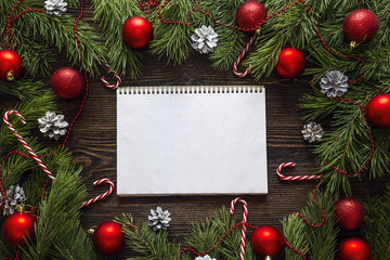 Fototapeta na wymiar Blank notebook with fir branches and Christmas decorations on wooden background. Space for text.