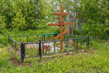 Grave with a wooden cross and a metal fence in a cemetery