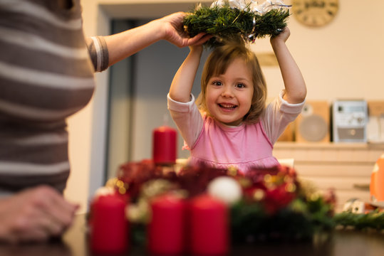 Little girl holding a christmas wreath above her head