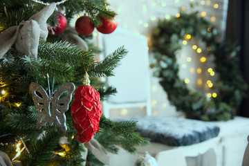 Red lump on a Christmas tree against a brick wall and a Christmas wreath