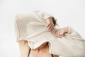 Young woman is taking off her sweater, covering her face. Lifestyle concept.