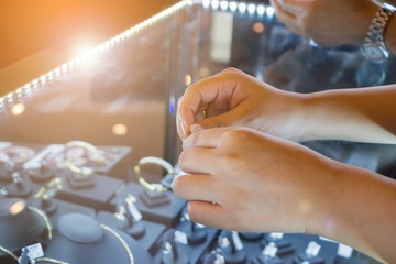 Asian woman choosing wedding rings at jewelry diamond shop