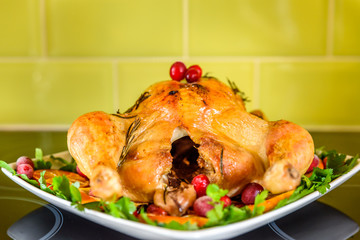 Closeup view of roasted chicken on white plate on kitchen table