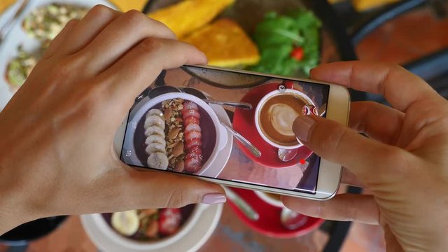 Closeup Blogger Hands Taking Picture Of Breakfast Food With Phone. Stylish Acai Smoothie Bowl And Coffee Latte In Hip Cafe. 4K. 
