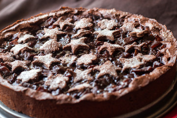 Homemade chocolate apple tart with filling, decorated with dough stars and sugar