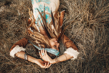 beautiful young boho girl in jacket lying down on grass