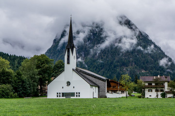 Fototapeta na wymiar Beautiful landscape with church and mountains at foggy summer day. Maurach, Tirol, Austria.