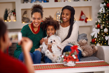 father making photo of mother with two daughters for Christmas.