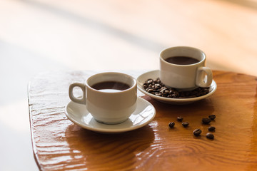 two white cups of black coffee on the table