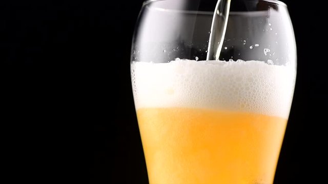 Cold beer pouring into a glass. Craft beer close up. Rotation 360 degrees. 4K video 3840x2160