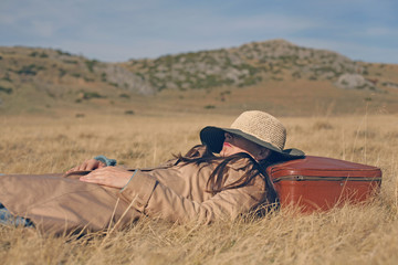 Woman traveler having a nap in a meadow; people, travel and nature concept.