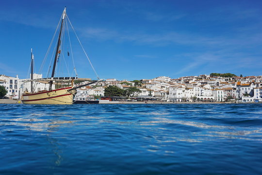 Spain a traditional boat and the village of Cadaques on the shore of the Mediterranean sea, seen from water surface, Costa Brava, Catalonia