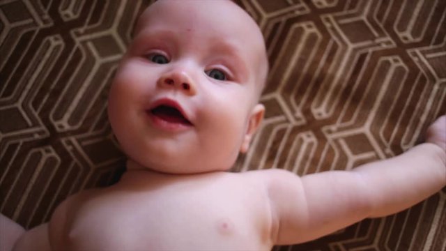 Cute baby lies on back and smiling (closeup) 