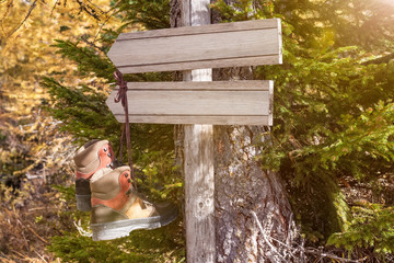 Wanderschuhe hängend auf Wegweiser Schild im Wald freie Textstelle Textfreiraum Fläche