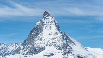 Snowy Matterhorn peak with blue sky and some clouds in background, Switzerland