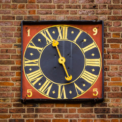 Ancient golden tower clock on a red brickwalll