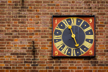Ancient golden tower clock on a red brickwalll