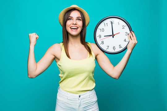 Young Excited Woman Holding A Clock Showing Nearly 9 With Happy Victory Emotions On Green Background