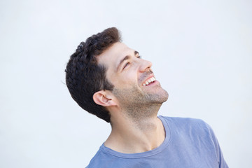 Close up cheerful young man smiling and looking away against white background