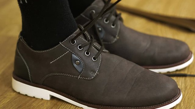 The man in a black socks wears shoes to tie shoelaces. Tying Boots.