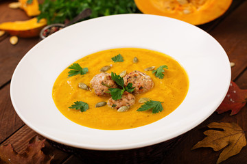 Delicious cream of pumpkin soup with meatballs made of turkey minced meat in a bowl on a wooden table. View from above. Thanksgiving Day.