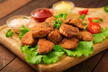 Chicken nuggets and sauce on a wooden background.