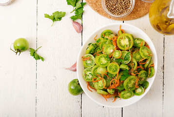 Korean salad from green tomatoes and carrots. Flat lay. Top view