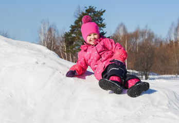 Fototapeta na wymiar Cheerful little girl on a walk a clear winter day.