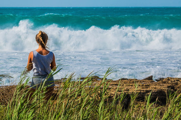 Frau sitzt am Meer