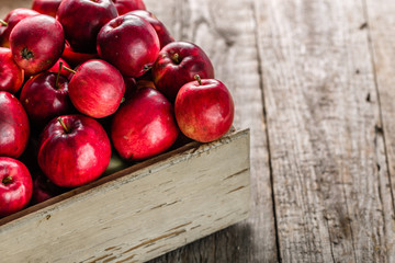 Red apples on table in wooden box, pile of fresh apple on rustic background