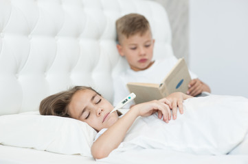 Obraz na płótnie Canvas Little boy reads the book to the sick sister