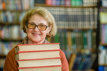 Smiling elderly woman with books in library. Space for text