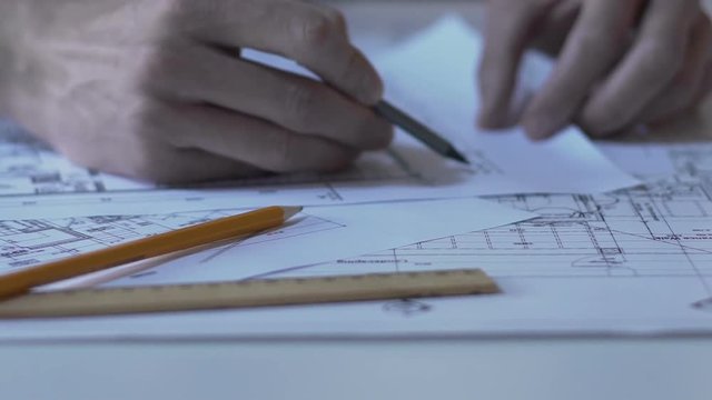 Architect checking building guidelines drawing, design bureau, hands closeup