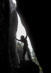 Woman in the dark cave with flaslight. back view. scenist girl between stones wall.