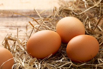 Fresh chicken eggs and straw on wooden background
