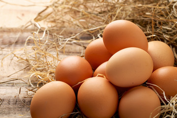 Fresh chicken eggs and straw on wooden background