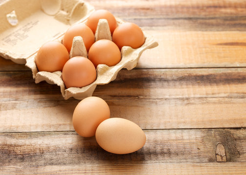 Fresh chicken eggs in egg box on wooden background
