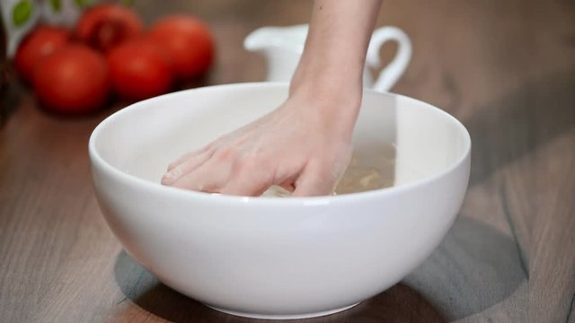 Making dough by female hands in white bowl