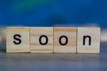 SOON word  on  wood cubes on table against blue background