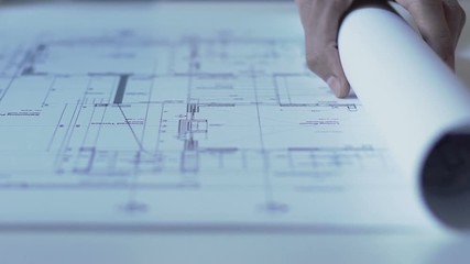 Hands of architect opening drawing of new building guidelines, design bureau - Powered by Adobe