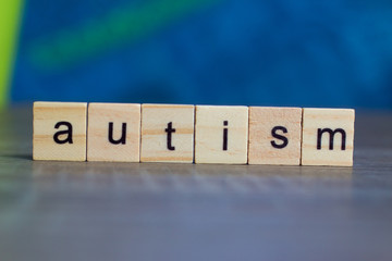 Autism word on wood cubes on table against blue background