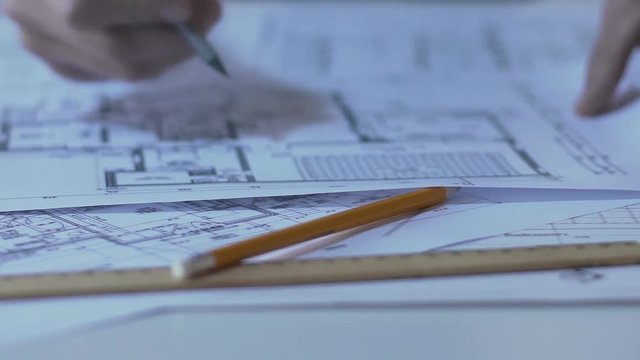 Male architect checking building layout, making notes and calculations, design