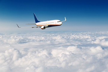 Fototapeta na wymiar Commercial airliner flying above clouds on blue sky background.